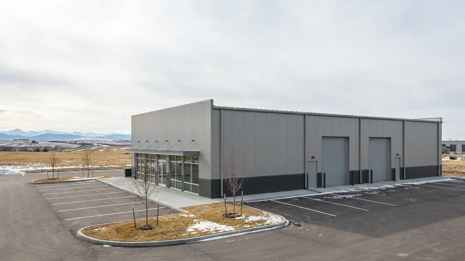 A single-storey steel commercial building with a glass storefront entry and overhead service doors on a paved lot