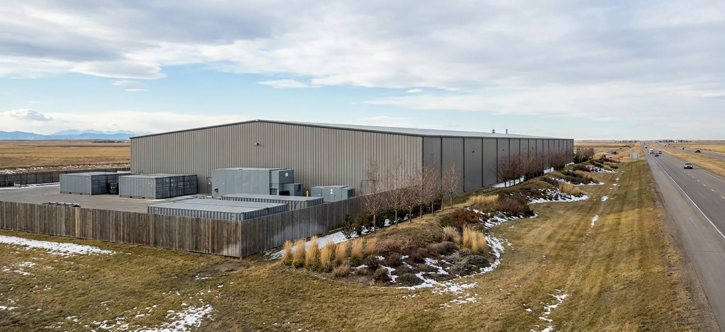 A steel industrial building with landscaped frontage and screened outdoor storage near a highway